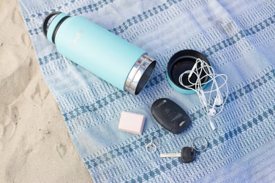 Turquoise stainless steel travel mugs, fob, keys and earplugs, USES blue fabric
